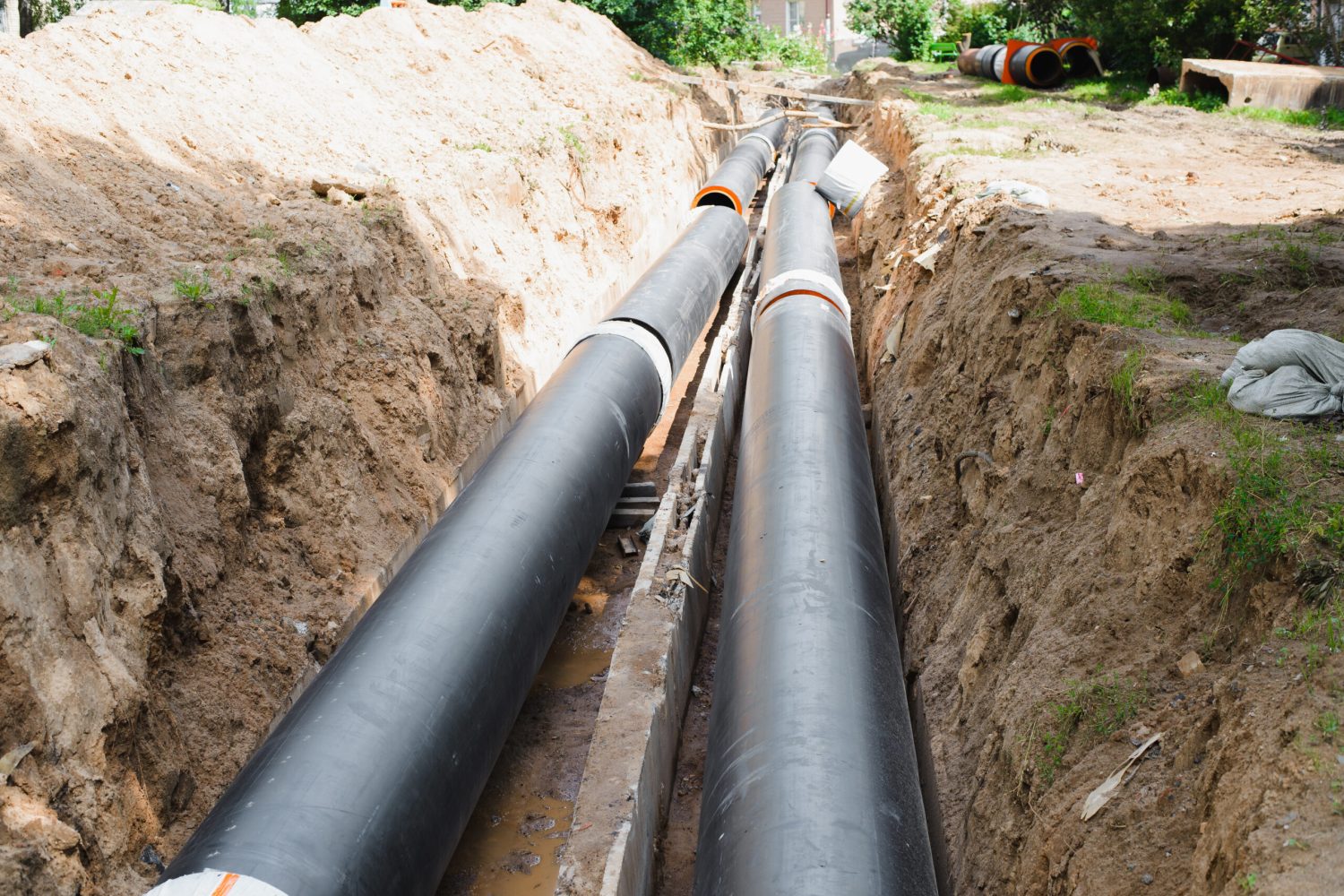 Plumbing repair. Installation of new industrial street water pipes in dug hole in two lines, outdoors.